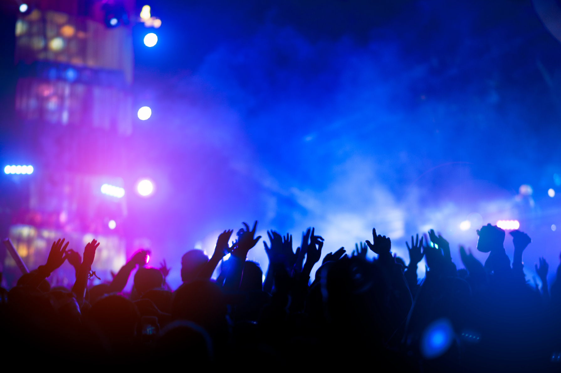 silhouettes of hand in concert.Light from the stage.confetti.the crowd of people silhouettes with their hands up.ribbon